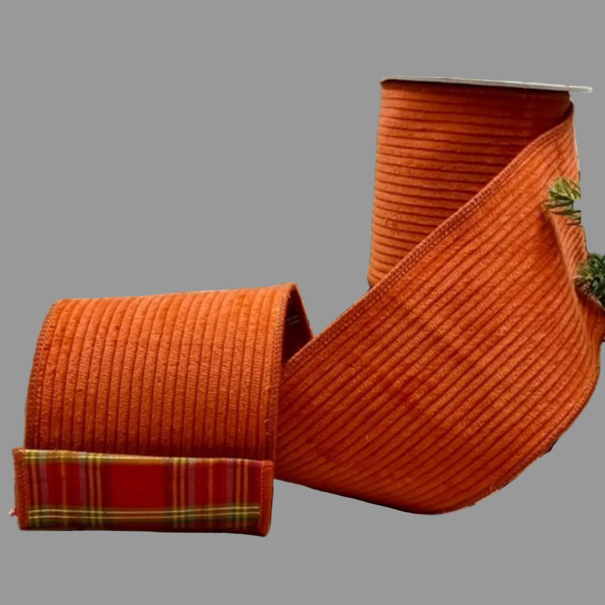 4-inch x 5-yard burnt orange designer ribbon made from 100% cotton, featuring a raised ribbed texture on the front and a contrasting red, gold, and green plaid backing.