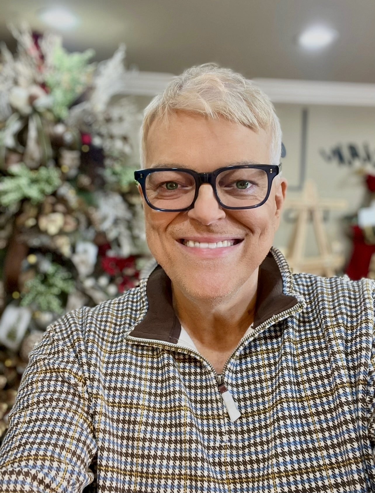 Image of Brian wearing glasses and a checkered shirt in a decorated room with a Christmas tree.