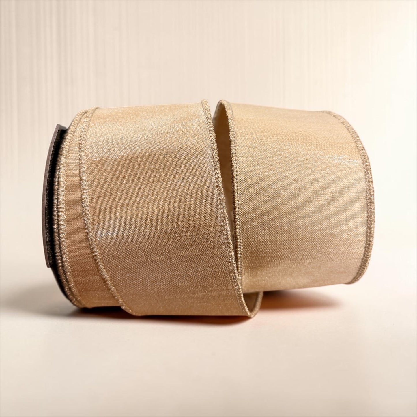 Gold D. Stevens 2.5-inch metallic dupioni wired designer ribbon with a soft shimmering finish, shown partially unrolled from the spool.