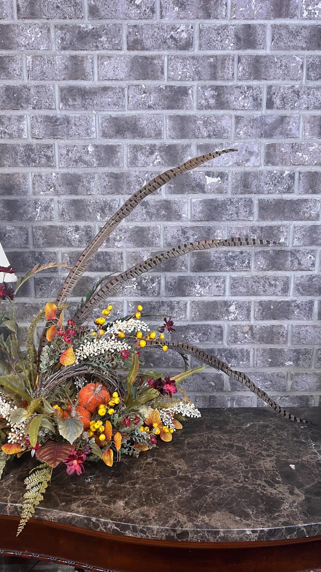 Eclectic “One of a Kind” Fall Grapevine Stand arrangement. Fuzzy Orange Jute wrapped stem pumpkins with golden berries with Pheasant Feather